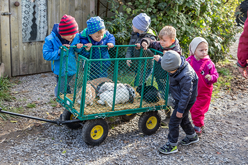 Kinder und ein Wagen mit Stall-Hasen