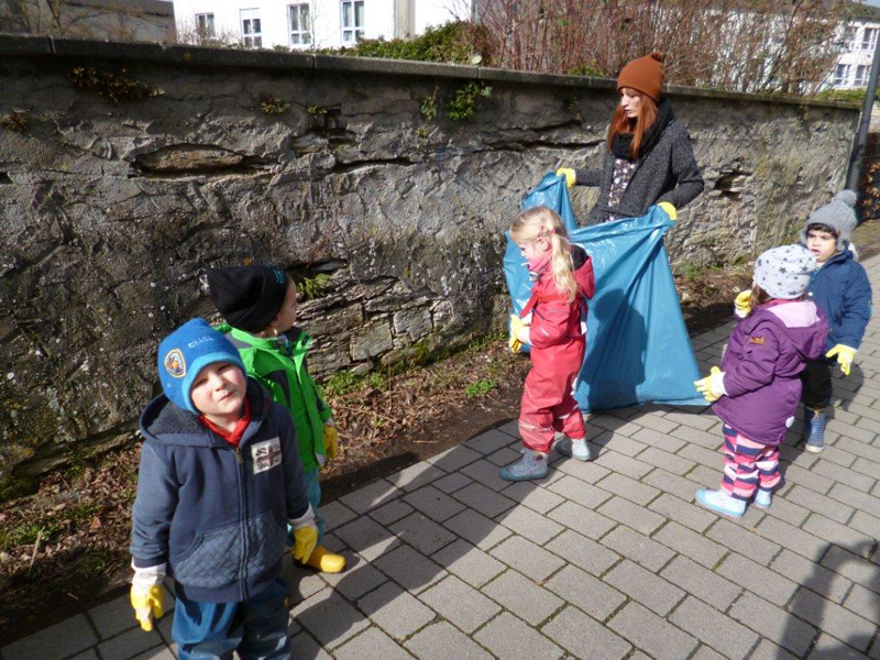 Kinder und Erzieherin mit großem Müllsack