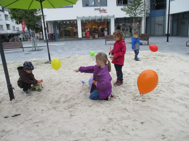 Kinder mit Luftballons und Windrädern