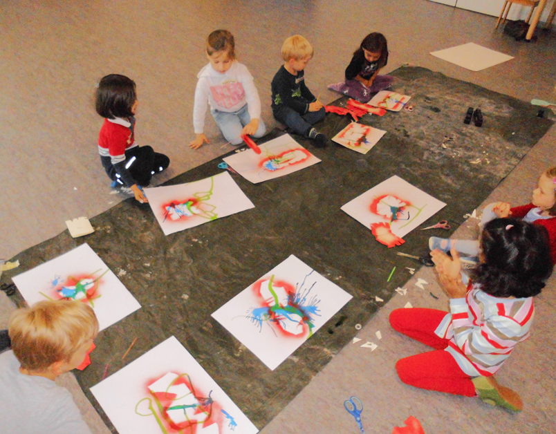 Kinder sitzen auf dem Boden und malen Bilder